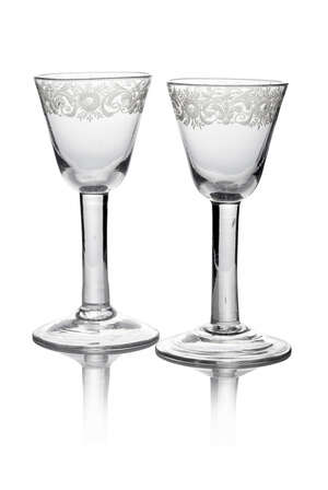 A pair of Dutch glasses, mid 18th century, with round funnel bowl, plain stem, arched conical foot with foliate border to bowl, 15.2cm high (2)