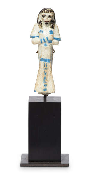 
	
		An Egyptian-style bichrome glazed faience shabti wearing a wig, details in turquoise,...