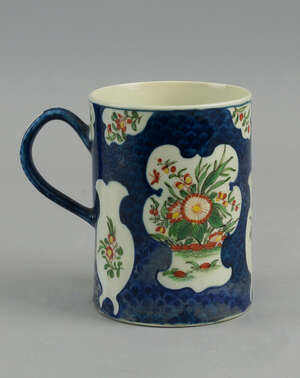 A Worcester cylindrical tankard, c. 1760, decorated with vignettes of flowers and sprays of flowers in the Kakeimon taste, on scale blue grounds, First period,