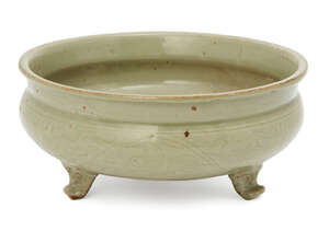 A Chinese Longquan celadon tripod censer, Ming dynasty, the everted rim above band of incised scrolling lotus flowers, the feet modelled as mythical beast mask