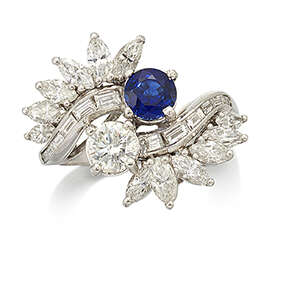 
	
		A platinum, sapphire and diamond cluster ring, of crossover design, with a single...