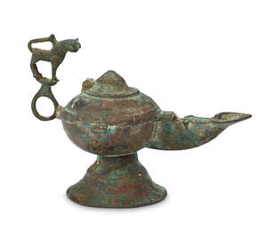 
	
		A Khorasan bronze oil lamp with lion handle, Iran, 12th-13th century, on a spreading...