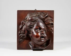 A carved wood plaque depicting a young child, 20th century, the child depicted looking off to...