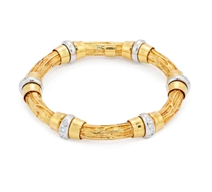 A diamond set flexible bracelet, designed as bark-textured cylindrical links with polished end...