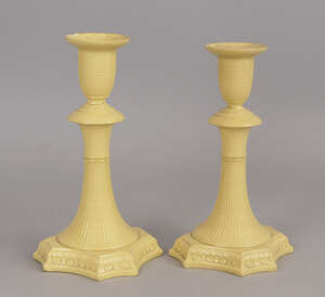 A pair of Wedgwood cane ware candlesticks, late 18th/early 19th century, with vase shaped candle nozzles and inverted trumpet form columns, on leaf cast square