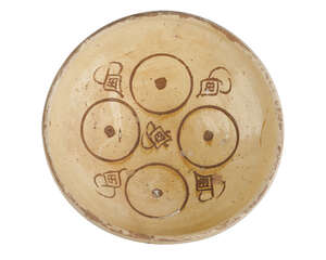 A Byzantine Sgraffito bowl, 12th century, the yellow glazed interior incised with four circles containing dots and abstract motifs, 26cm. diam.  
		 
		 
