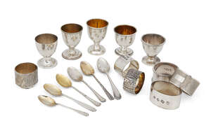 A quantity of silver eggcups and napkin rings, all in individual boxes, comprising: five silver and silver gilt eggcup and spoon sets, one initialled, one eggc