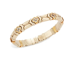 A diamond set sprung torque bangle, composed of quatrefoil shaped diamond clusters, between...