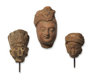 Three small red stone heads, India, 10th-12th century, one with finely moulded features, two with metal pins, 5.5cm. 7cm. and 4.2cm. high (3)
