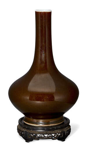 A Chinese porcelain monochrome teadust glazed bottle vase, Jiaqing period, covered in a mottled brown-green glaze, unmarked, 29.5cm high, on carved hardwood st