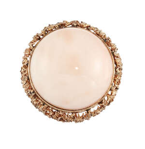A pink coral bombe ring, the polished coral cabochon measuring 21mm dia. to a pierced and textured mount, ring size G½