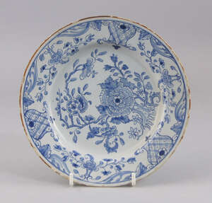 A Continental tin glazed earthenware plate, 19th century, decorated with Chinese flowers to the centre, with floral displays to the rim, in dispersed with shie