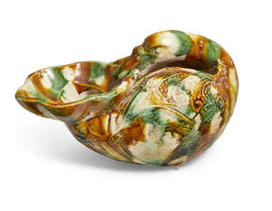 A Chinese sancai-glazed rhyton shaped as a goose, Tang dynasty, the vessel is potted as a recumbent goose with its neck arched back over its body clutching a f