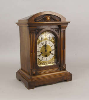 
	
		An Edwardian walnut mantel clock, the case of architectural style with arched glass and...