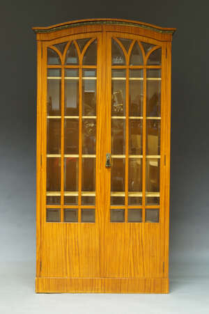 
	
		An ash veneered display cabinet, early 20th Century, possibly German, the curved moulded...