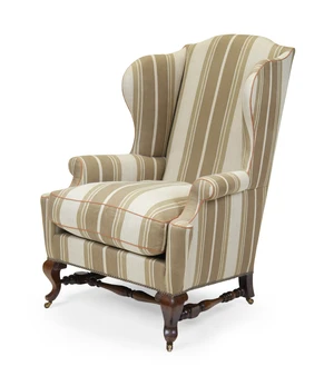 An Edwardian mahogany wingback armchair by Howard & Sons, first quarter 20th century, on cabriole feet and castors, joined by turned stretchers, the back left 