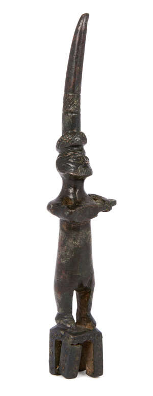 A Hittite bronze figure of a bearded man playing a musical instrument, circa 1500B.C., shown wearing a tall hat and holding a rectangular instrument with curve