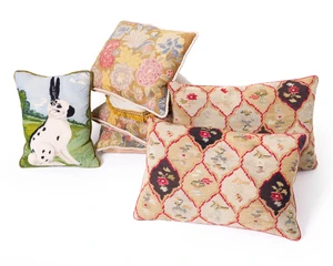 A pair of English needlework cushions, the needlework late 19th century, with a lozenge design outlined in red centred by floral sprays, 40 x 60cm; together wi