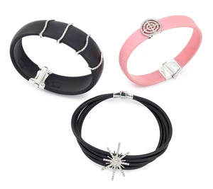 A group of three rubber bracelets, in black and pale pink rubber, one composed of multiple rows,...