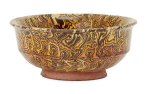 A Chinese marbled-pottery bowl, Tang dynasty, with steep straight sides to flared rim, covered in a translucent amber glaze stopping neatly before the foot, 10