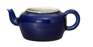 A Chinese porcelain monochrome blue-glazed teapot, Yongzheng mark and of the period, of squat shouldered form with simple loop handle, covered in a thick dark 