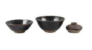 Three pieces of Chinese stoneware, Song dynasty, comprising two black-glazed bowls, 16.5cm and 18cm diameter, and a compressed jar, 5.5cm high
