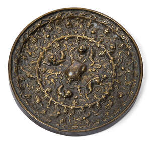 
	
		A Chinese bronze 'lion and grape' mirror, Tang dynasty, cast with a central lion-shaped...