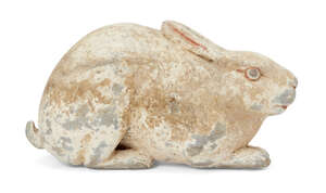 A Chinese grey pottery hare, Han dynasty, modelled crouching facing forwards in alert pose with long ears folded back, bulging eyes and flared nostrils, with f