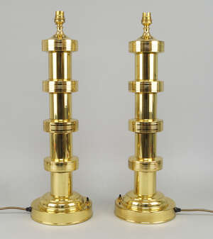 
	
		A pair of polished column lamps, with four ring form collars, on a domed and cylindrical...