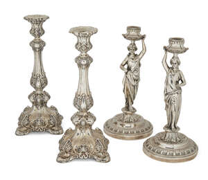 Two pairs of white metal candlesticks, the first, designed as ladies carrying urns raised on a stepped circular foot to tree stump pedestal, 29cm high, the sec
