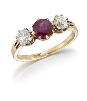 
	
		A ruby and diamond three stone ring, the central circular-cut ruby between old mine-cut...