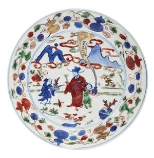 A Chinese porcelain wucai dish, Wanli mark and period, painted with a scholar and a boy being presented with a coral tree in a mountainous landscape, inside a 