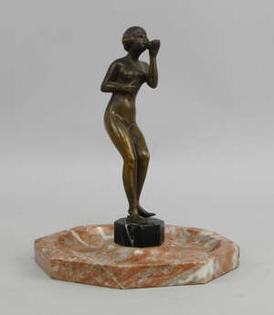 
	
		An Art Deco bronze and marble ash tray, 20th century, mounted with a figure of a nude...