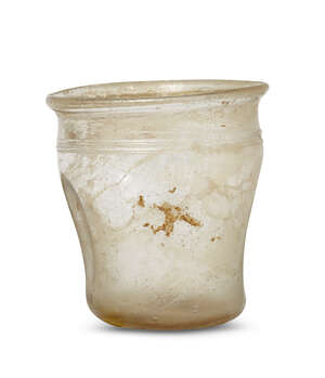 
	
		A Roman glass cup, 2nd-4th century AD, with compressed sides, on a perspex plinth, cup...