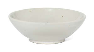 A Chinese Xing white-glazed bowl, Tang dynasty, the shallow, thickly potted bowl with rounded sides rising from a neatly cut bi-shaped foot with chamfered rim,