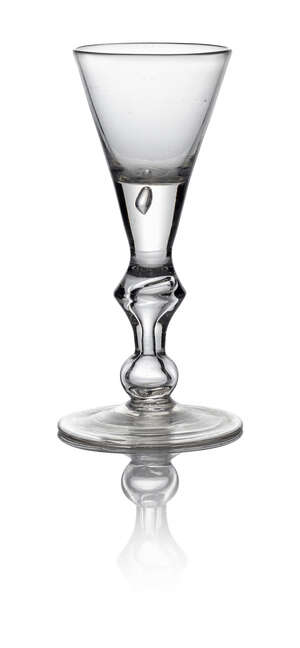 A Queen Anne heavy baluster drinking glass, c. 1710, with conical bowl, on knopped stem with spreading double foot, 14.5cm high