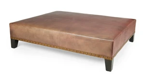 A large modern leather ottoman, by Sibyl Colefax & John Fowler, with studded gilt leather trim, on ebonised feet, 40cm high, 160cm wide, 131cm deep
Provenance: