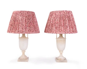A pair of alabaster urn table lamps, second half 20th century, each with twin handles above a tapering body on socle support on square base, with pleated fabri