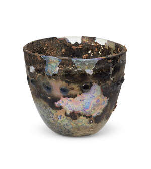 
	
		A heavily-weathered late Roman glass beaker, 4th century A.D., decorated with a...