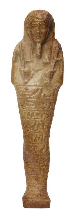 An Egyptian green glazed composition shabti of typical form holding an adze and hoe with a seed-bag over the left shoulder, with ten lines of impressed hierogl