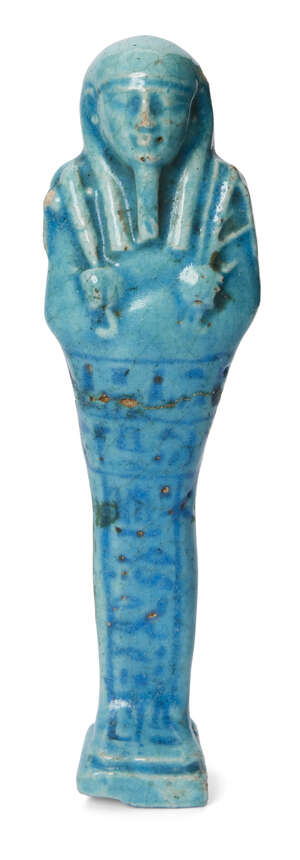 An Egyptian bright blue glazed composition shabti of typical form holding a pick and hoe with a seed-bag over the left shoulder, with double T-crossbar hierogl