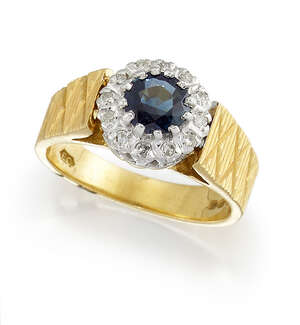 An 18ct gold, sapphire and diamond ring, the circular-cut sapphire within a single-cut diamond surround, to a tapered, reeded hoop with engraved cross pattern 