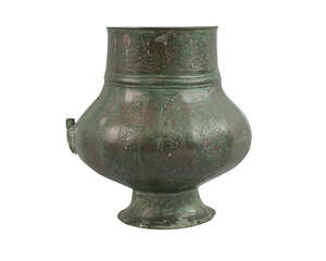 A Khorasan silver-inlaid bronze vase, Iran, 12th century, on a splayed foot, decorated to body with vertical panels of scrolling vine, the neck with inlaid ani