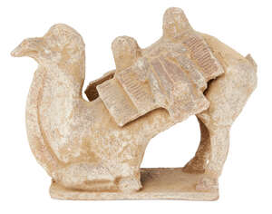 A Chinese pottery model of a caparisoned camel, Tang dynasty, the camel modelled resting on its front legs, 22cm high