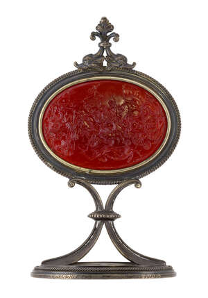 A late 19th century silver mounted glass intaglio desk ornament,  the oval intaglio depicting a scene from the Trojan wars, in framed mount with twin dolphin s