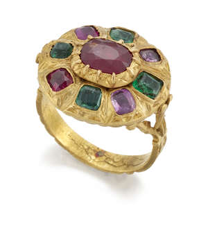 A ruby and emerald ring, of oval cluster design, the central oval ruby to a surround of alternate square or cushion shaped rubies and emerald, all in closed ba