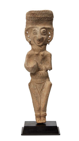 A Cypriot terracotta figure, circa 1000 B.C., modelled as a Goddess with an incised headdress, necklace and belt and pierced ears, holding a vessel against her