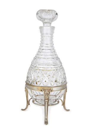A rounded cut glass decanter raised on a silver stand, London, c.1973, Asprey & Co., the silver stand supported by three curved, reeded feet with acanthus leaf