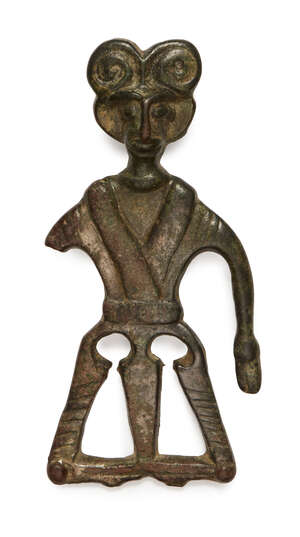 An Amlash bronze statue, 1st millennium B.C., depicting a figure with elaborate curled hair, wearing a robe which crosses at the waist, one arm deficient, two 