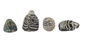 Four Roman glass gaming pieces, 1st-4th century AD, the larges of combed glass with knop finial, a green glass conical piece, a further combed glass piece and 